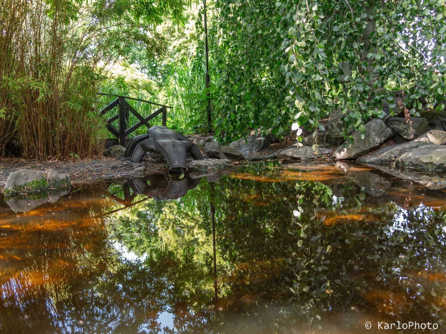 A crocodile made from car tires at a pond in a park.