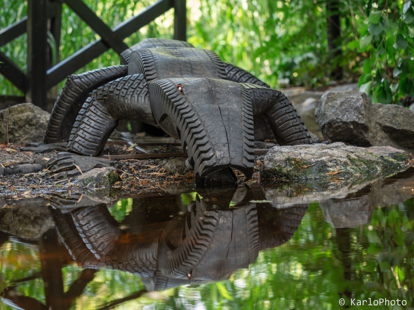 A crocodile made from car tires at a pond in a park.
