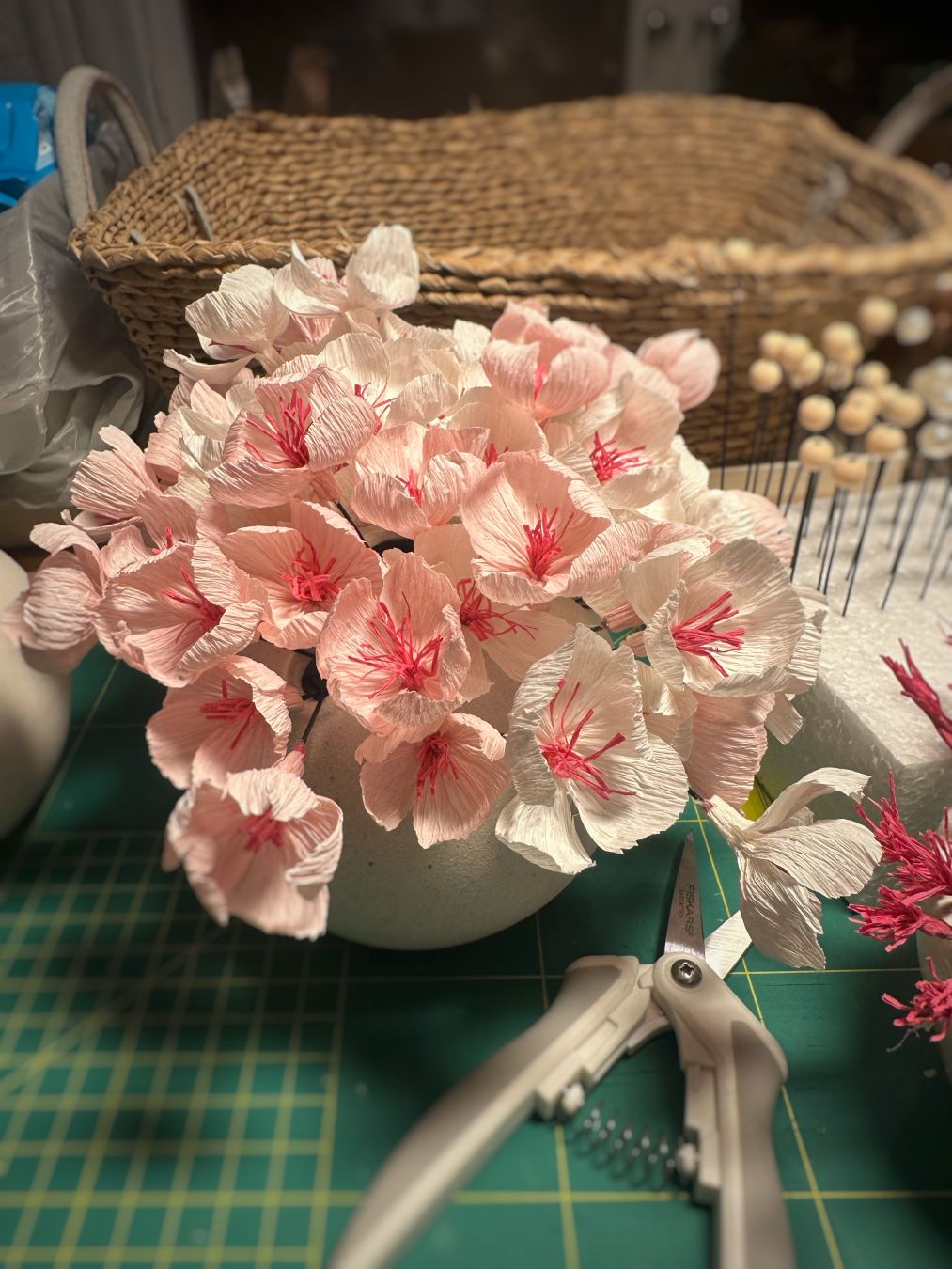 54 pink and white flowers in a small white vase and a work desk