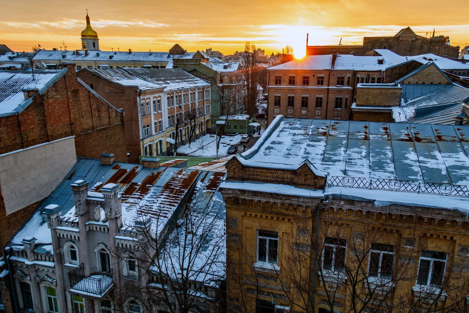 Utsikt över några äldre hus i centrala Kiev, solnedgång, till vänstern ett klocktorn med gyllene kupol.