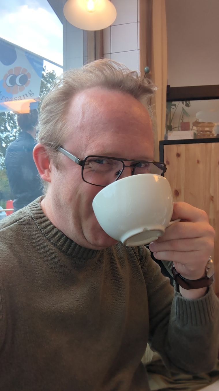 Selfie. Jag sitter i ett fönster och dricker te ur en liten, rund mugg. Jag ler med hela ansiktet bakom tekoppen.